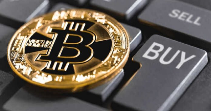 A bitcoin sitting on top of a computer keyboard with buttons labeled buy and sell