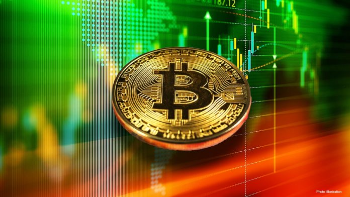 Picture of a bitcoin in front of green charts with red on the bottom